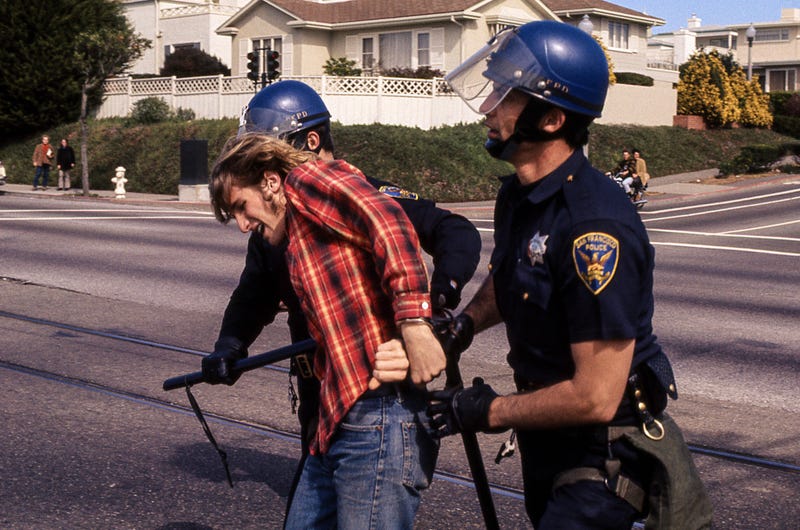 This image features two San Francisco police officers holding batons arresting a man.