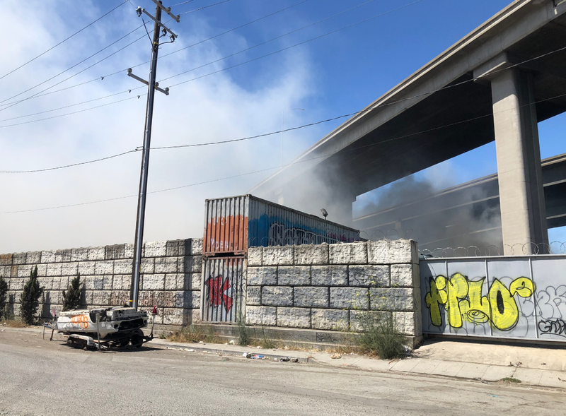 Smoke rises from an encampment fire in Oakland on Monday morning.