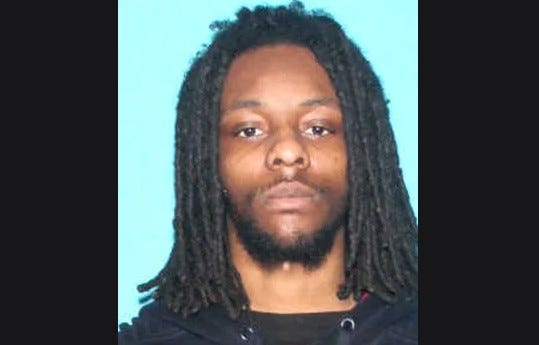 Mugshot of Black man in 20s with dreads