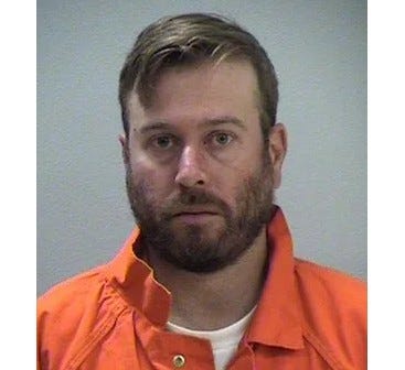 White bearded man in 30's mugshot wearing orange collard button down