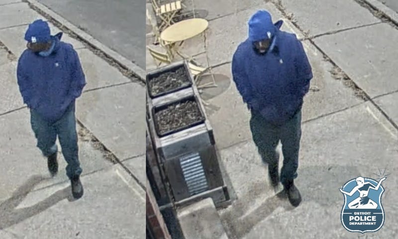 Black man wearing blue jeans, blue hoodie and blue beanie walking on sidewalk