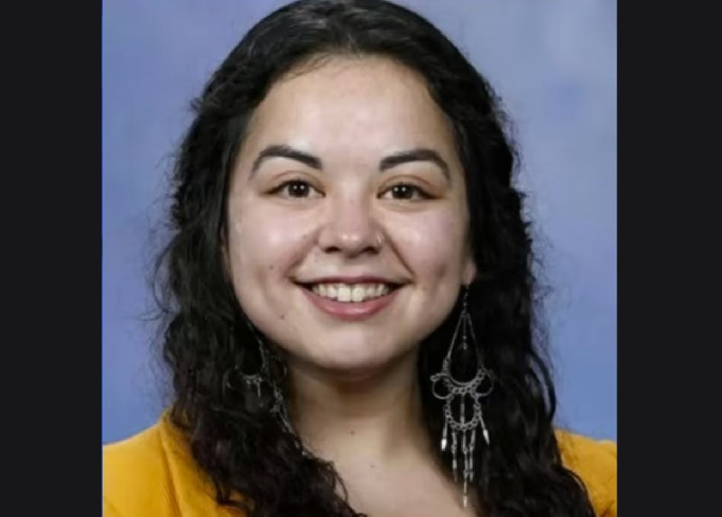 Woman in her 20s smiling with dark curly hair, wearing dangly earrings and yellow shirt