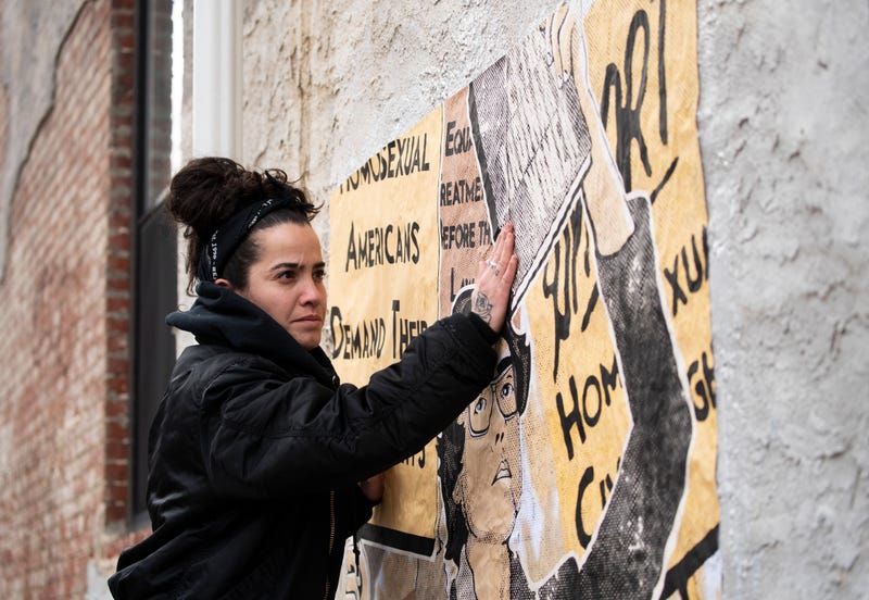 Marisa Velázquez-Rivas putting up posters featuring Barbara Gitting, a gay pioneer who fought for equal employment.
