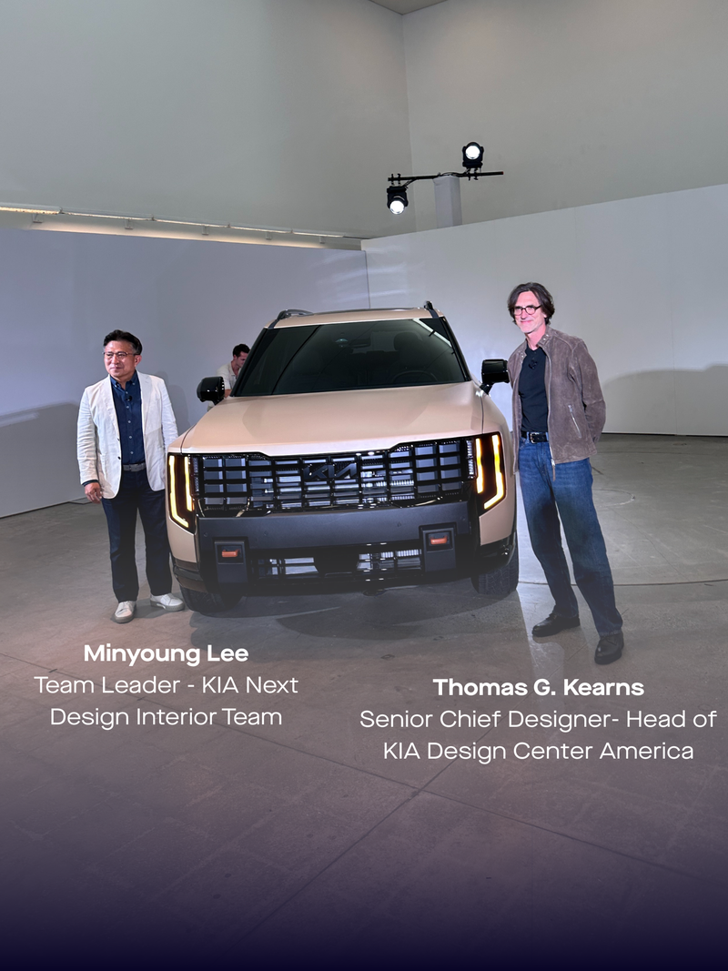 Two people stand beside a modern beige SUV in a spacious, well-lit showroom. The vehicle's design features bold vertical headlights, creating a sleek, futuristic look.