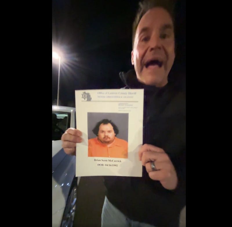 Genesee Co. Sheriff Swanson holding photo of Scott McCarrick