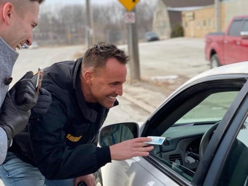 Genesee County Sheriff Chris Swanson handing gift card to driver