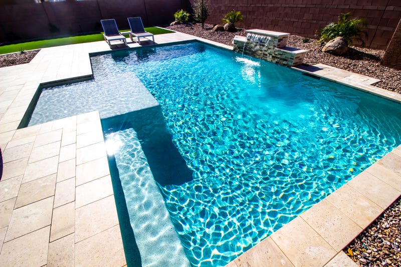 Back Yard With Two Lounge Recliner Chairs And Swimming Pool With Waterfall