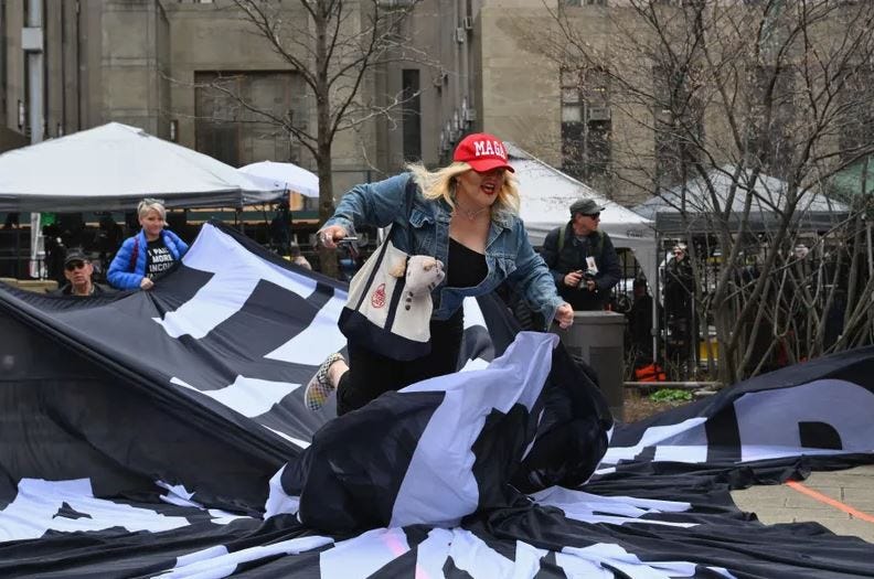 A Trump supporter rushes an anti-Trump banner outside Manhattan Criminal Court on April 4, 2023.