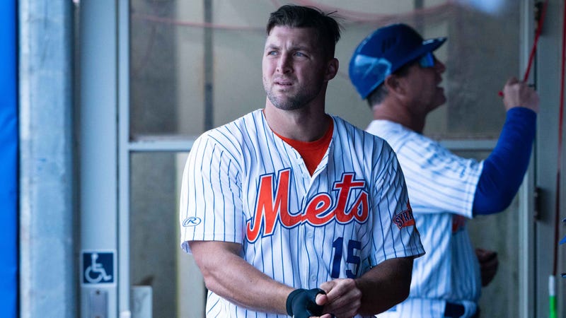 Tim Tebow takes off his batting gloves in the dugout of the Triple-A Syracuse Mets.