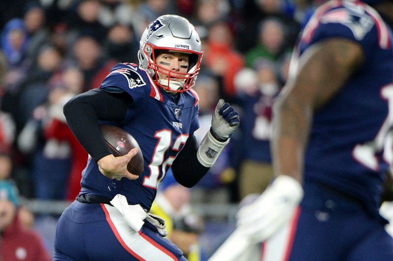 QB Tom Brady evades defenders in pursuit.
