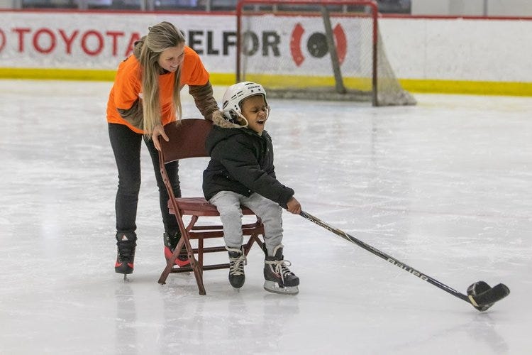 A visually impaired child playing hockey along with a woman helping him.