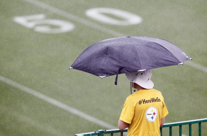 A staff member looks over the fields as rain delays the start of Pittsburgh Steelers training camp 