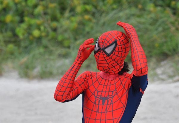 Man dressed in Spider-Man costume on the beach