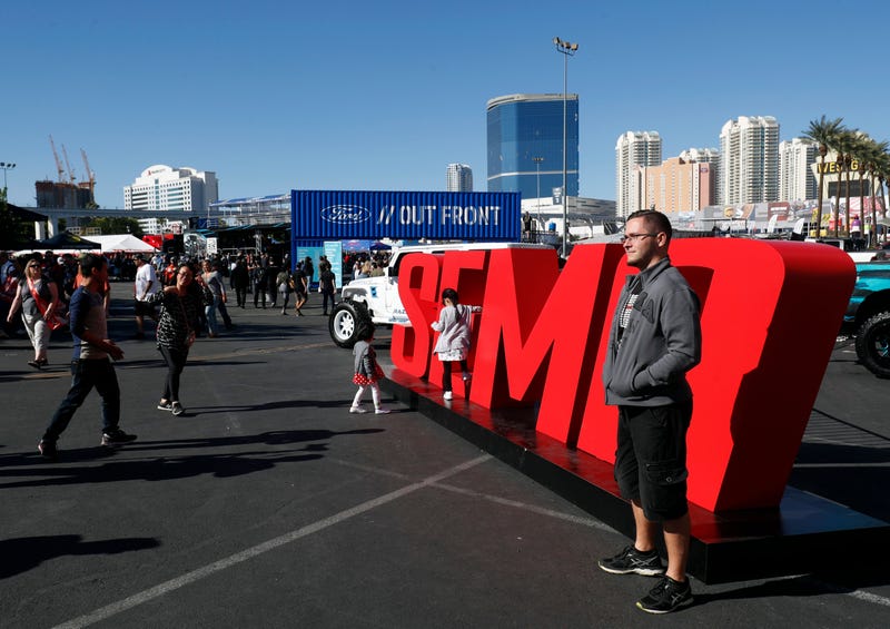 Attendees pose by a SEMA sign at the Las Vegas Convention Center.