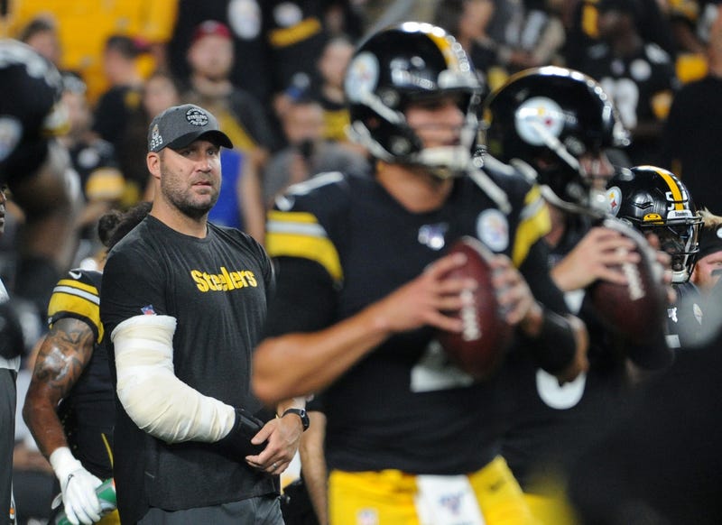 An injured Ben Roethlisberger watches young quarterbacks warm up before a game