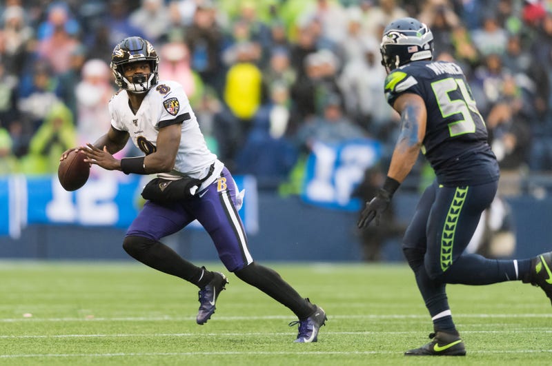 Ravens quarterback Lamar Jackson (8) looks for an open receiver while being defended by Seattle Seahawks middle linebacker Bobby Wagner (54)