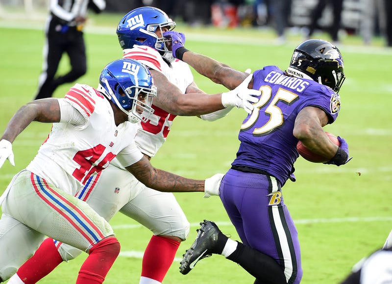 Gus Edwards stiff-arms a Giants defender during Sunday's 27-13 win.