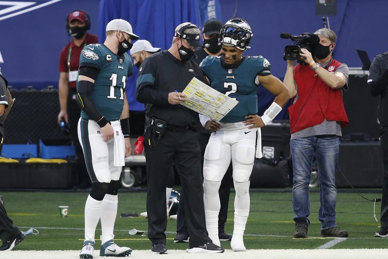 Philadelphia Eagles quarterbacks Carson Wentz (11) and Jalen Hurts (2) talk with head coach Doug Pederson (C) during a timeout against the Dallas Cowboys in the second quarter at AT&T Stadium.