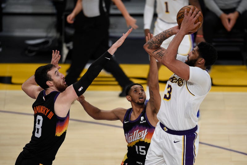 Lakers star Anthony Davis shoots a jumper over two Suns players.
