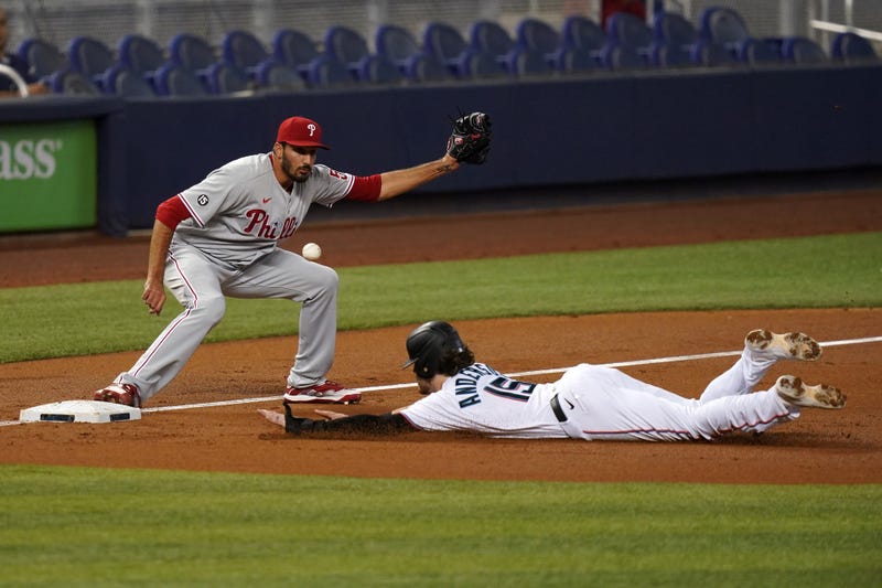 Miami Marlins third baseman Brian Anderson (15) dives safely into third base as Philadelphia Phillies starting pitcher Zach Eflin (56) covers in the second inning at LoanDepot Park.