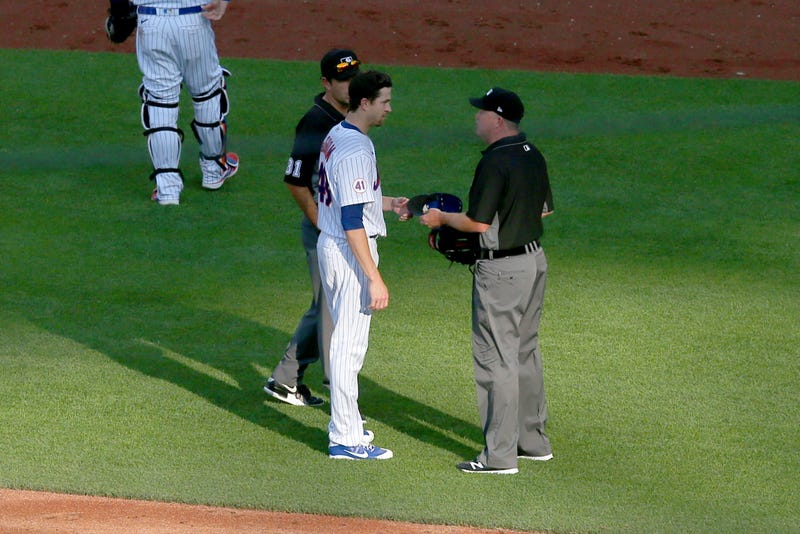 MLB umpires checking Jacob deGrom's hat and glove.
