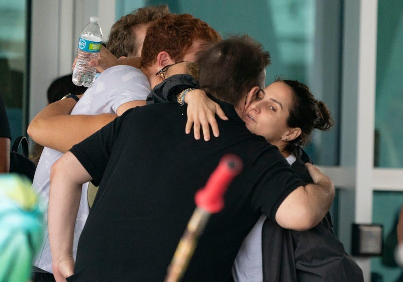 People hug outside the Surfside Community Center as they wait for news on June 25, 2021 in Surfside, Florida. The 12-story Champlain Towers South condo building partially collapsed on Thursday in Surfside, Florida