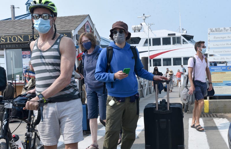 Masked passengers arrive on the Boston fast ferry on MacMillan Pier in Provincetown, Mass. 