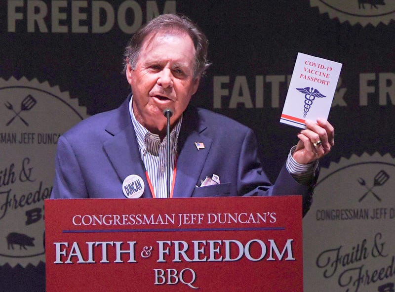 Bob McLain Show host of 106.3 FM holds a booklet with the U.S. Constitution, with the words COVID-19 Vaccine Passport on the cover, during Congressman Jeff Duncan's 10th annual Faith and Freedom BBQ at the Civic Center of Anderson Monday, August 23, 2021.