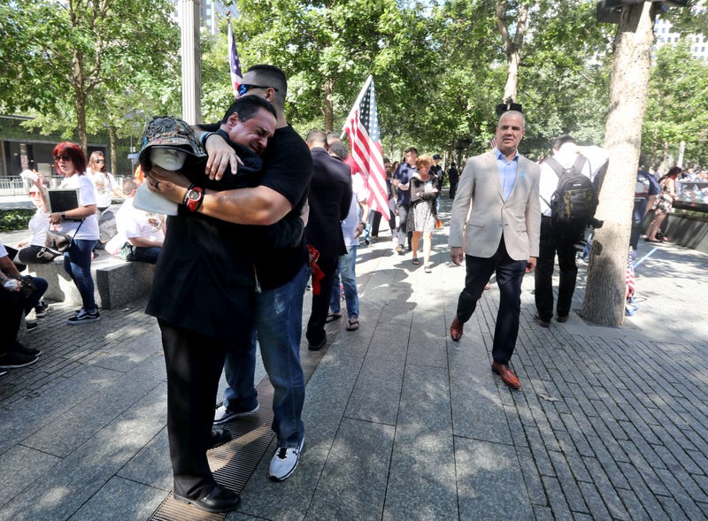 Mario Miranda, left, a retired member of the New York City Police Department, is embraced by fellow NYPD member Eloy Suarez as they both attend the ceremony marking the 20th anniversary of the Sept. 11th attacks at the 9/11 Memorial in New York City Sept. 11, 2021. Suarez was a first responder to the World Trade Center the day of the attacks in 2001. 