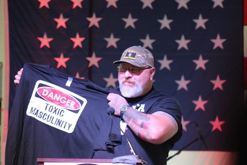 Teddy Daniels, a GOP congressional candidate, holds a shirt that reads "Danger: Toxic Masculinity". 