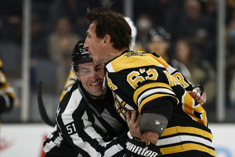 Boston Bruins left wing Brad Marchand (63) is held back by linesman Andrew Smith