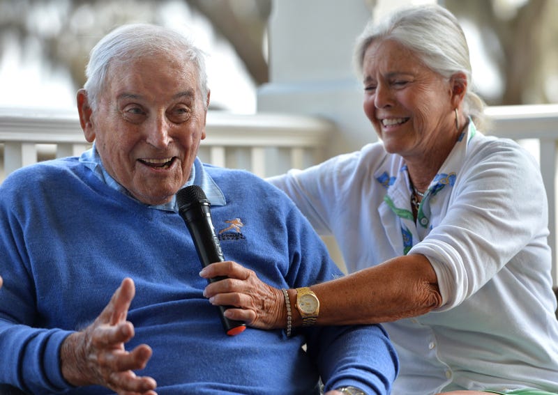 Mary Lujack, right, holds a microphone for her father, Johnny Lujack, winner of the 1947 Heisman Memorial Trophy at The Founder's Club on Tuesday. Lujack spoke to members on the veranda of the clubhouse after accompanying his daughter and some of her friends on the golf course