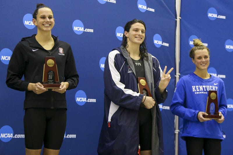 Penn Quakers swimmer Lia Thomas stands between Stanford Cardinal swimmer Lillie Nordmann Kentucky Wildcats swimmer Riley Gaines