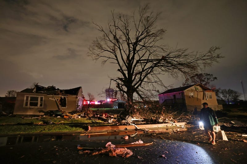 A man carries jugs of water past heavily damaged houses in Arabi, Louisiana after an apparent tornado touched down on Tuesday evening, March 22, 2022.