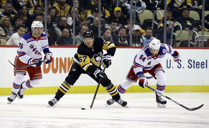 Pittsburgh Penguins right wing Rickard Rakell (67) skates with the puck between New York Rangers center Jonny Brodzinski (76)