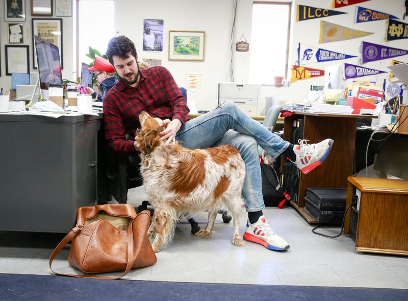 Tom Cullen pets Peach, the newsroom dog, at the Storm Lake Times office