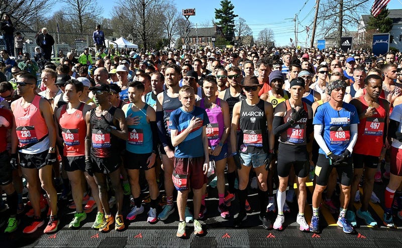The first wave of runners stand for the national anthem