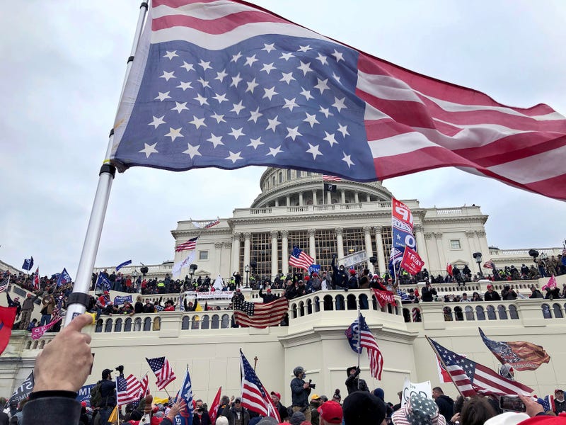 An inverted American flag waves over the pro-Trump mob that took over the steps of the Capitol in Washington, DC, Wednesday, January 6, 2021 Capitol Takeover