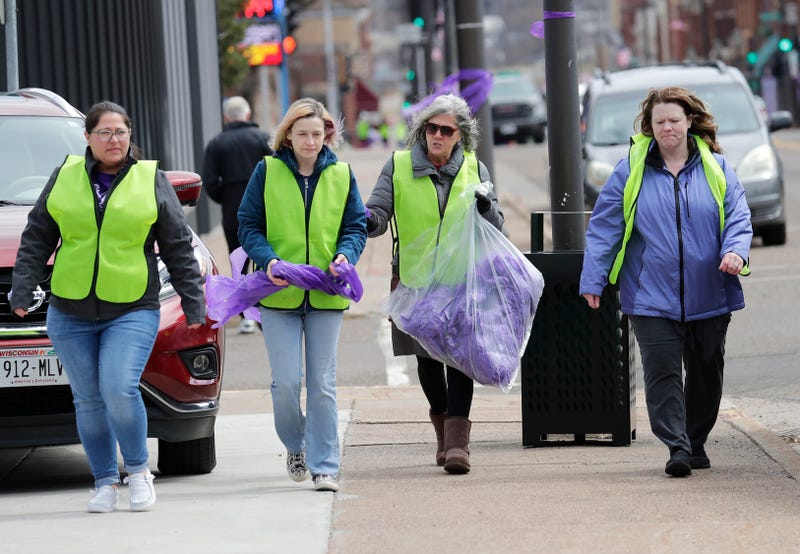 A group of women hang purple ribbons in downtown Chippewa Falls, Wisconsin as officials investigated the homicide of Lily Peters, 10, Tuesday, April 26, 2022.