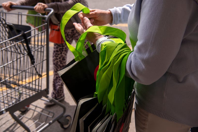 Woman hands out reusable bags outside grocery store