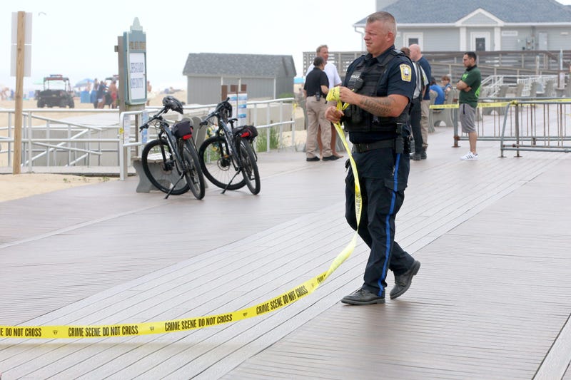 A Belmar police officer wrap up crime scene tape that spanned the boardwalk near where a person drowned in the ocean adjacent to the 8th Avenue beach jetty in the town Monday afternoon, June 13, 2022