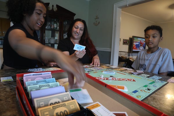 Raquel Kooper with her daughter Lilly 18 and son Josias 9 sit at home and play Monopoly