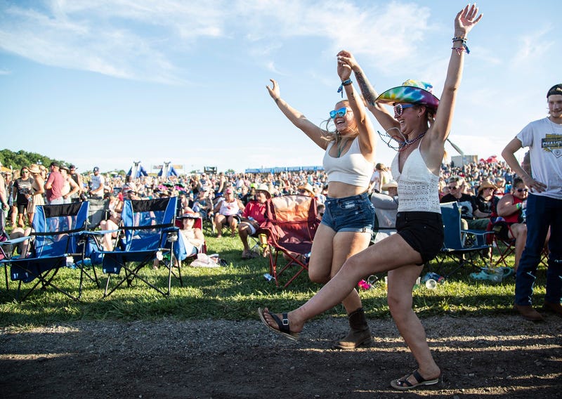 Country music fans dance as they wait for Jake Owen to perform on stage during Faster Horses festival in 2022