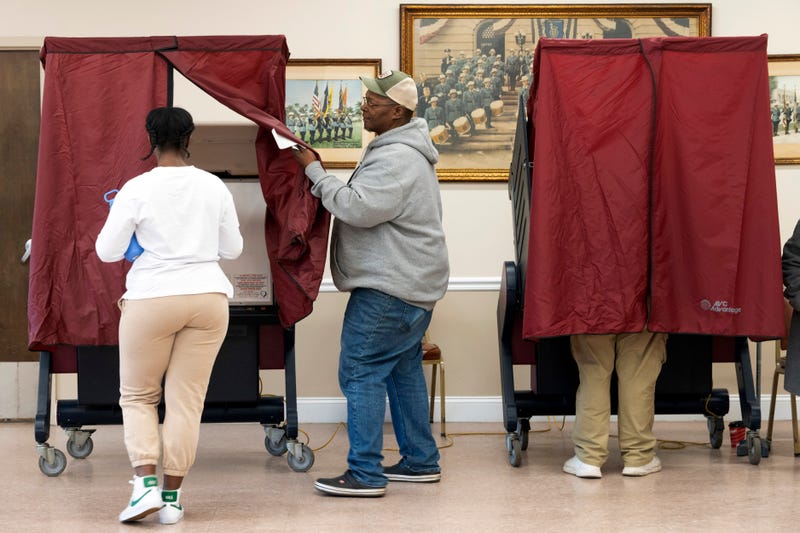 A poll worker opens up a curtain for a voter as she enters the voting booth at the Civic Center in Hackensack on Nov. 8, 2022