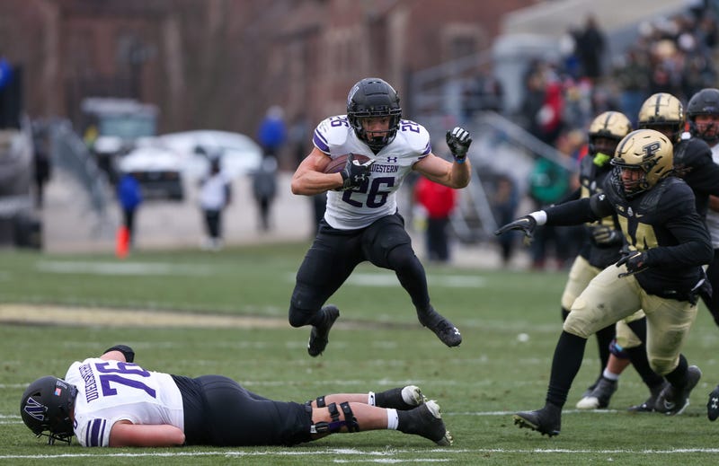 Northwestern Wildcat Evan Hull (26) jumps over offensive lineman Ethan Wiederkehr (76) as he runs away from the Purdue Boilermaker defense during the NCAA football game, Saturday, Nov. 19, 2022, at Ross-Ade Stadium in West Lafayette, Ind