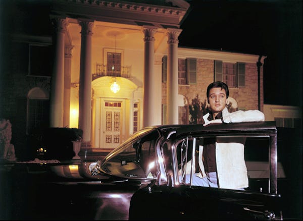 Elvis Presley posing with one of his cars outside Graceland