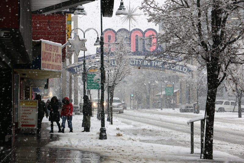 People walk in downtown as snow falls in Reno on Dec. 31, 2022