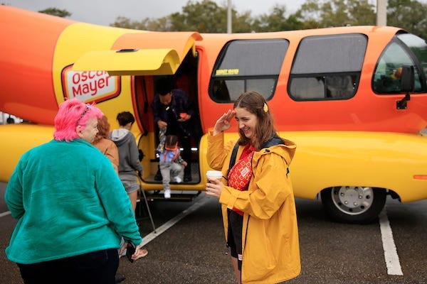 Katherine "Sauerkraut Kat" Abraham salutes patrons as Terri Hubner, left, looks on outside the Oscar Mayer Wienermobile Friday, Feb. 3, 2023 at the Jacksonville Humane Society in Jacksonville, Fla
