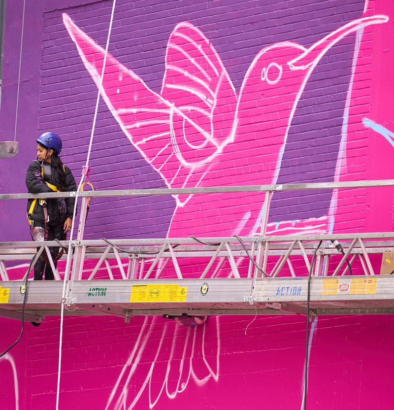 Lucinda Hinojos, also known as La Morena, stands under the wings of a hummingbird featured on the Super Bowl LVII mural on the side of a building on the corner of First and Washington streets in Phoenix on Jan. 23, 2023. La Morena Mural