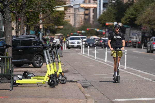 A pedestrian rides an electric scooter down Congress Avenue on Monday Feb. 6, 2023 in Austin